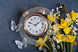 Spring time, daylight savings concept, spring forward concept. Alarm clock with spring flowers top view