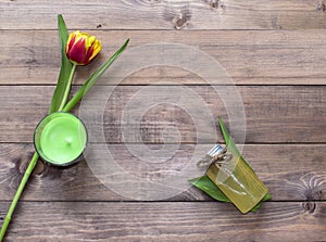 Spring tulip flower with candle and cosmetic product on wooden background.Flat lay view with copy space