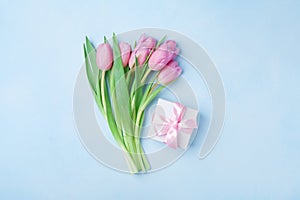 Spring tulip flowers and gift box on blue pastel table top view. Greeting card for Birthday, Womans or Mothers Day. Flat lay.