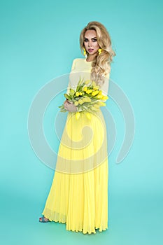 Spring Woman. Beauty Summer model girl with colorful clothes, holding a bouquet of spring yellow flowers.