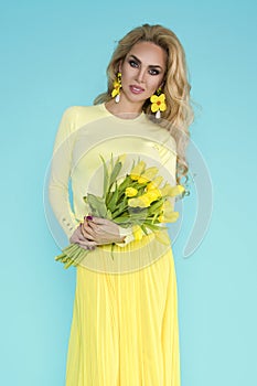 Spring Woman. Beauty Summer model girl with colorful clothes, holding a bouquet of spring yellow flowers.