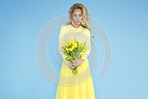 Spring Woman. Beauty Summer model girl with colorful clothes, holding a bouquet of spring yellow flowers.