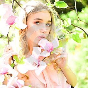 Spring woman in flower bloom. Womens day with girl in pink blossom. Magnolia flower beauty in nature. Skincare and