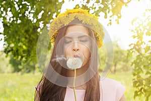 Spring woman portrait. Young woman blowing on a dandelion