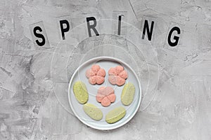 SPRING word and flower cookies on a plate on a gray background . Spring holidays cooking concept