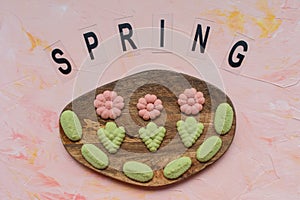 SPRING word and flower cookies on a wooden board on a pink background . Spring holidays cooking concept