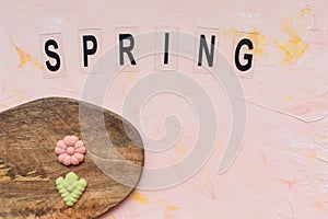 SPRING word and flower cookies on a wooden board on a pink background . Spring holidays cooking concept