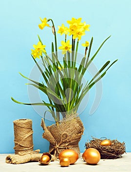 Spring yellow narcissus, golden easter egg and thread or rope