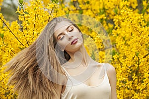 Spring young woman with natural makeup and healthy long brown hair in blossom park outdoors. Natural female beauty portrait