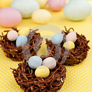Springtime chocolate nests filled with Easter eggs on yellow photo