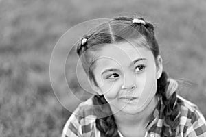 Springtime concept. Cute daydreamer. Girl little kid spend leisure outdoors in park. Girl sit on grass in park. Child photo