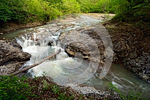 Springtime landscape of mountain river with small waterfall over rocks