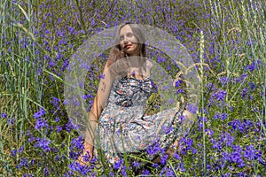 Springtime portrait of brunette girl into meadow violet flowers