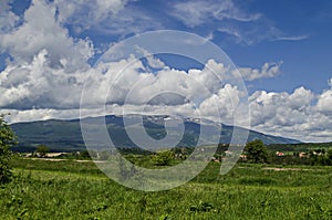 Springtime scene with mountain glade, forest and residential district of bulgarian village Plana at Plana mountain