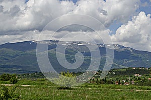 Springtime scene with mountain glade, forest and residential district of bulgarian village Plana at Plana mountain