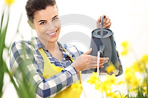 Springtime, smiling woman in garden with watering can