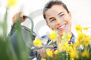 Springtime, smiling woman in garden with watering can