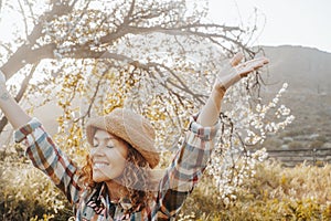 Springtime. Welcome spring concept image with overjoyed happy woman raising arms and closing eyes hugging and loving nature around