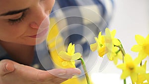 Springtime, woman in garden touches and smells narcissus