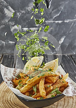 Sprinkle parsley on potatoes with parsley and lemon, fried in oil on wooden board