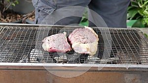 Sprinkle salt and pepper over the roast beef on the iron rack over the charcoal grill.