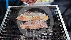 Sprinkle salt and pepper over the roast beef on the iron rack over the charcoal grill.