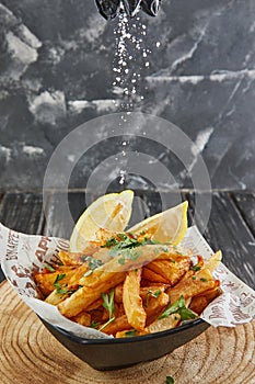 Sprinkle salt on potatoes with parsley and lemon, fried in oil on a wooden board