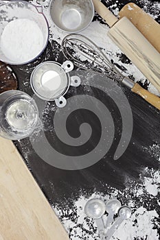 Sprinkle wheat flour with copy space for text on dark black wood background, top view for cooking dough or pastry background