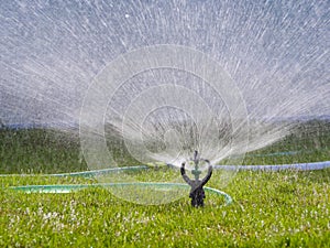 Sprinkler splashing the water to green grass field