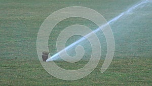 Sprinkler system working on fresh green grass on football, soccer stadium