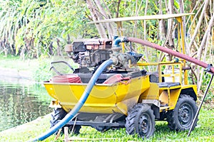 Sprinkler truck small old yellow water pump is watering trees in park.