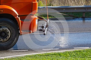 Sprinkler truck is washing the street with shampoo in the early morning. Municipal vehicles for cleaning city road
