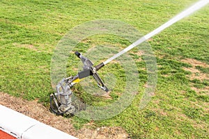 Sprinkler and water hose in grass field stadium