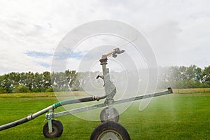 Sprinkler watering agricultural field in the sun Irrigation plant in agriculture under bright sunlight . Agriculture watering