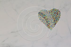 Sprinkles arranged in a heart shape on a white grey marble rustic background. Valentine's Day, greeting card. Sprinklers photo