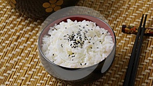 Sprinkling black roasted sesame seeds on a bowl with traditional Japanese rice