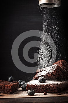 Sprinkling chocolate brownie with icing sugar vertical