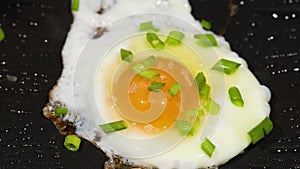 Sprinkling green scallion on sunny side up eggs