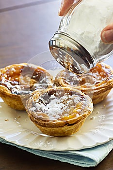 Sprinkling Powdered Sugar Over Pasteis de Nata photo