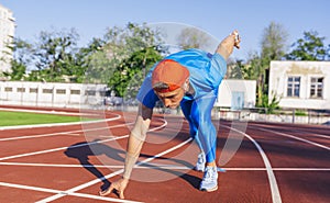 Sprinter athlete male at starting position ready to start a race. Man sprinter ready for sports exercise on racetrack in stadium.