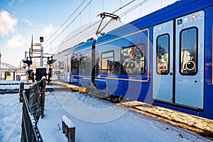 Sprinter electric passenger train running on snow covered tracks at railway crossing