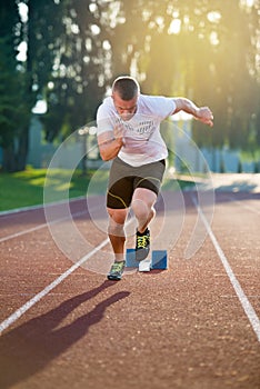 Sprinter leaving starting blocks on the running track. Explosive start.