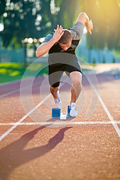 Sprinter leaving starting blocks on the running track. Explosive start.