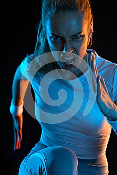 Sprinter run. Strong athletic woman running on black background wearing in the sportswear. Fitness and sport motivation