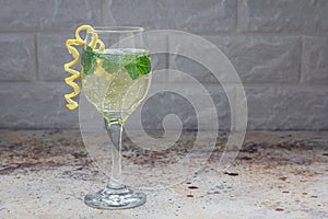 Spritzer cocktail with white wine, mint and ice, decorated with spiral lemon zest, copy space