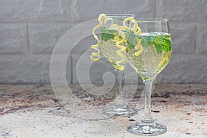 Spritzer cocktail with white wine, mint and ice, decorated with spiral lemon zest, copy space photo