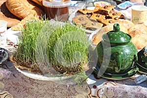 sprouted wheat, a symbol of the Navruz holiday, and a teapot on the table