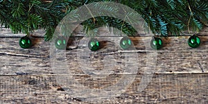 Spruce branches with Christmas tree decorations are laid out on a wooden natural background.Place for text