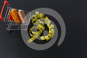 Spun polyester sewing thread and tailor tape on black background