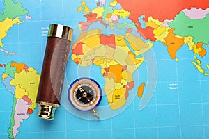 Spyglass and compass on world map. Travel planning concept